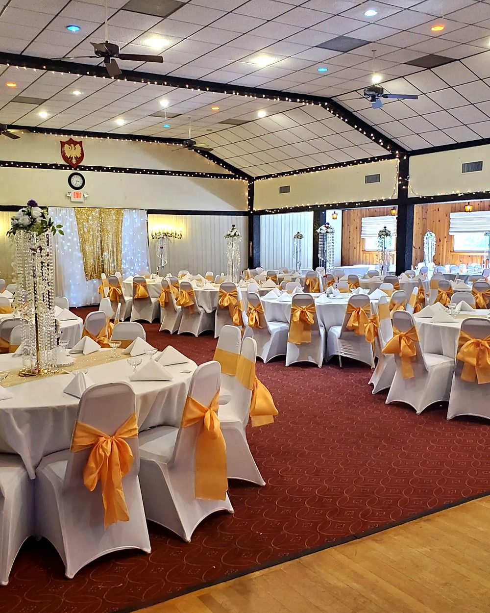 PACA Events banquet room set for a formal celebration with gold sashes, crystal centerpieces, and string lights