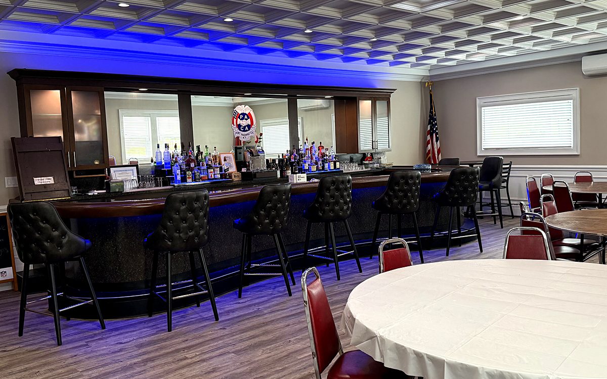 Front bar room with curved bar, blue LED lighting, and seating for up to 50 guests