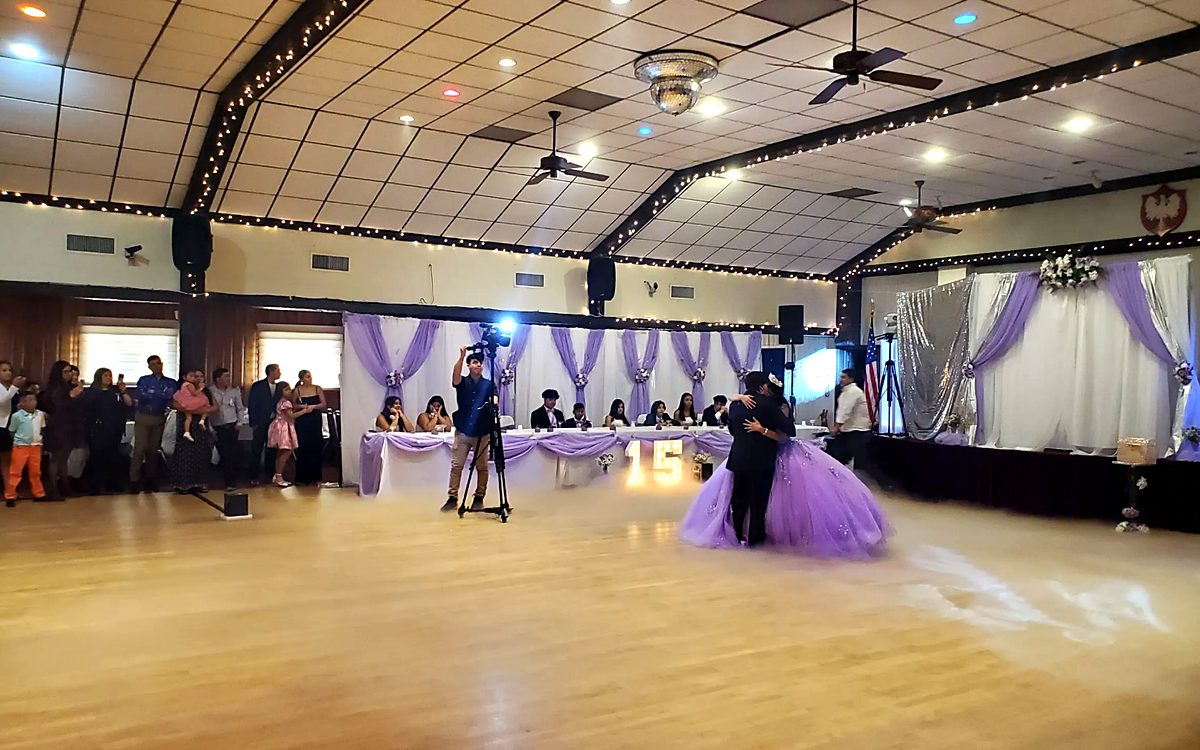 Grand banquet room with 2000 sq ft wood dance floor, stage, and purple draping for a quinceañera celebration